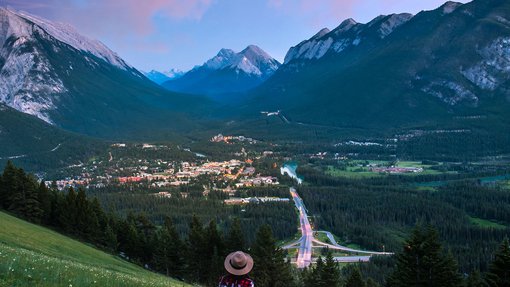 Woman and dog overlooking summer mountain town. Banff.