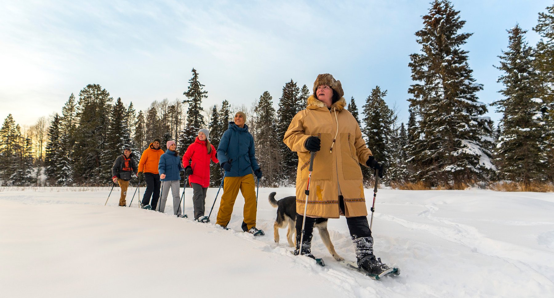 A group of people on a guided snowshoe walk across a lake.