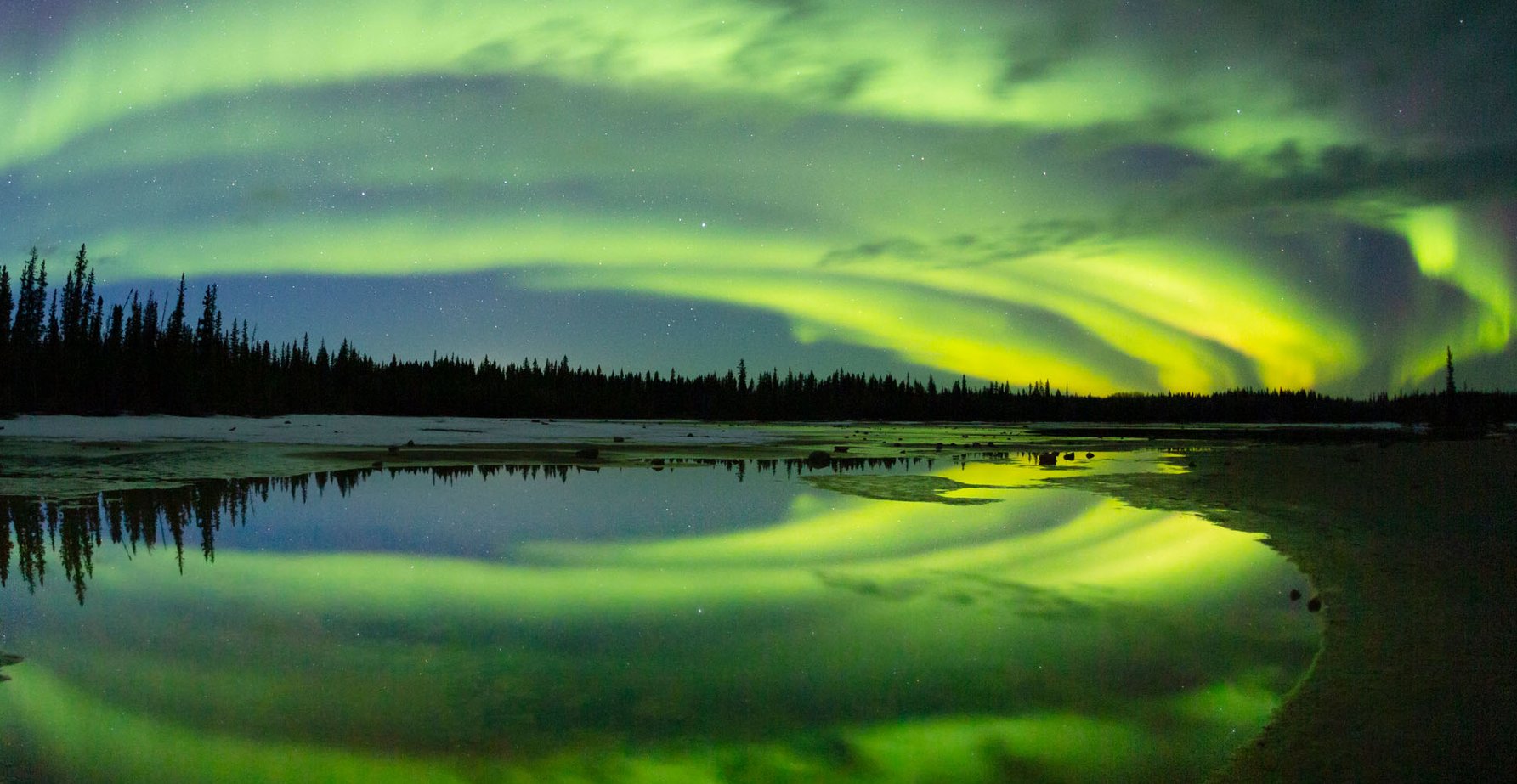 Northern lights stretch across the sky over a lake in Wood Buffalo National Park.